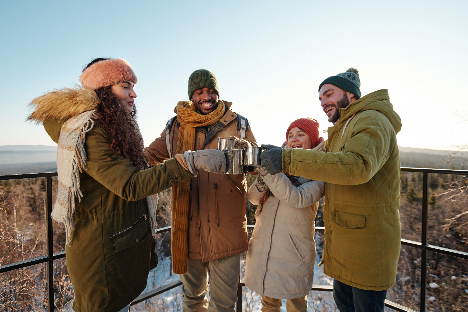 Equipa a brindar com canecas ao pôr do sol num miradouro de inverno